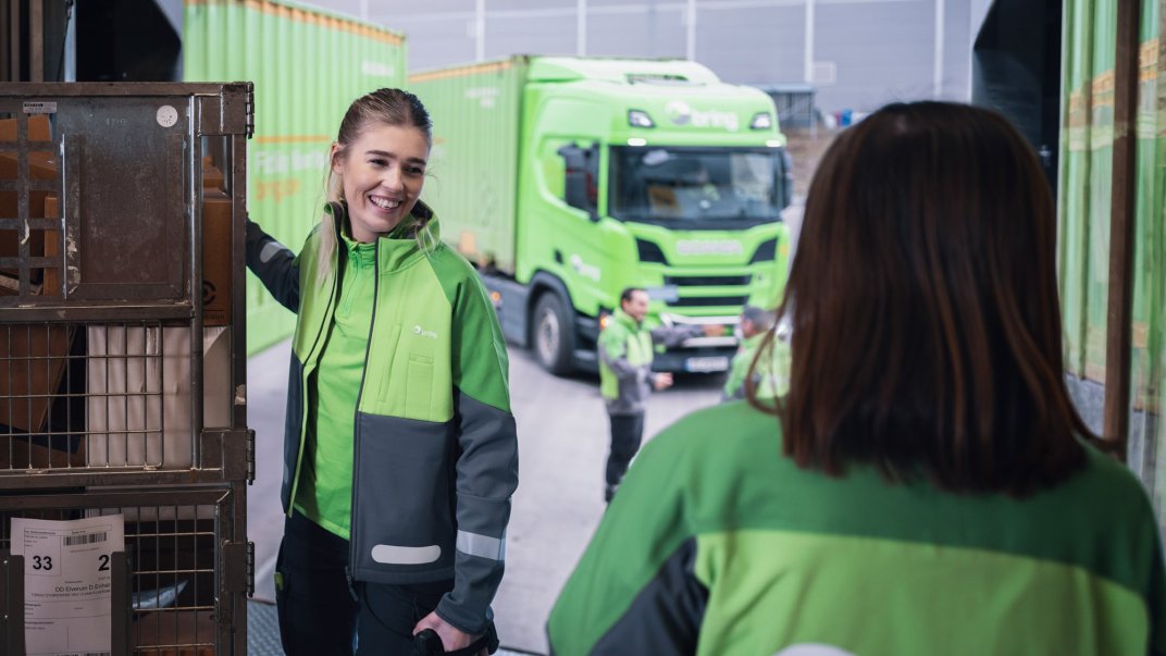 Woman holding a parcel container in front of a truck