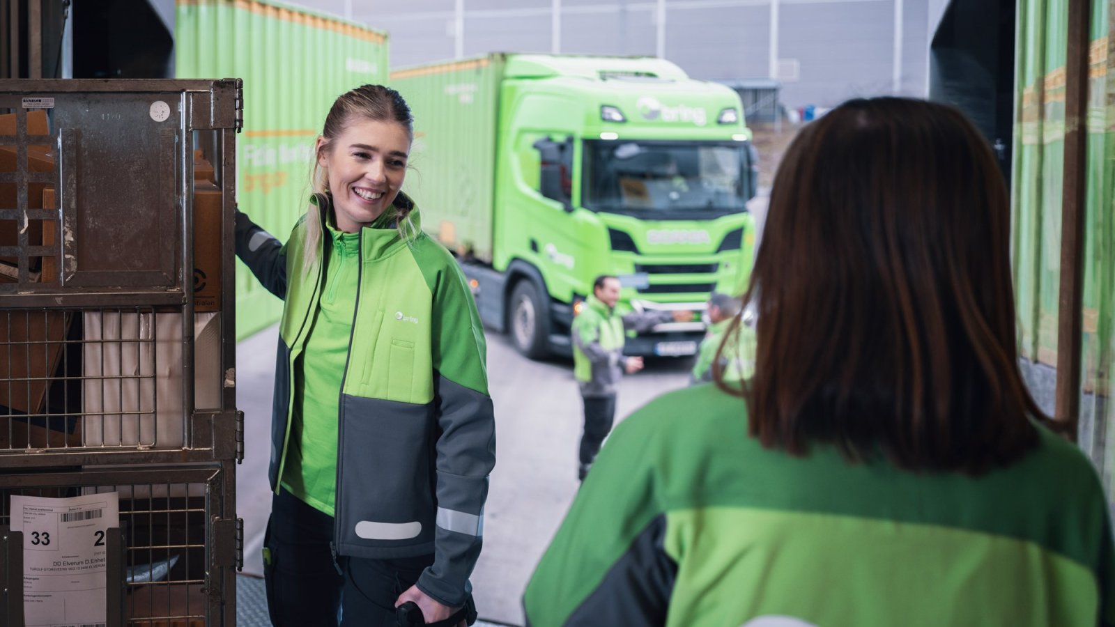 Woman holding a parcel container in front of a truck